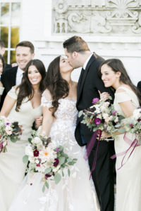 bride and groom kissing between bridal party