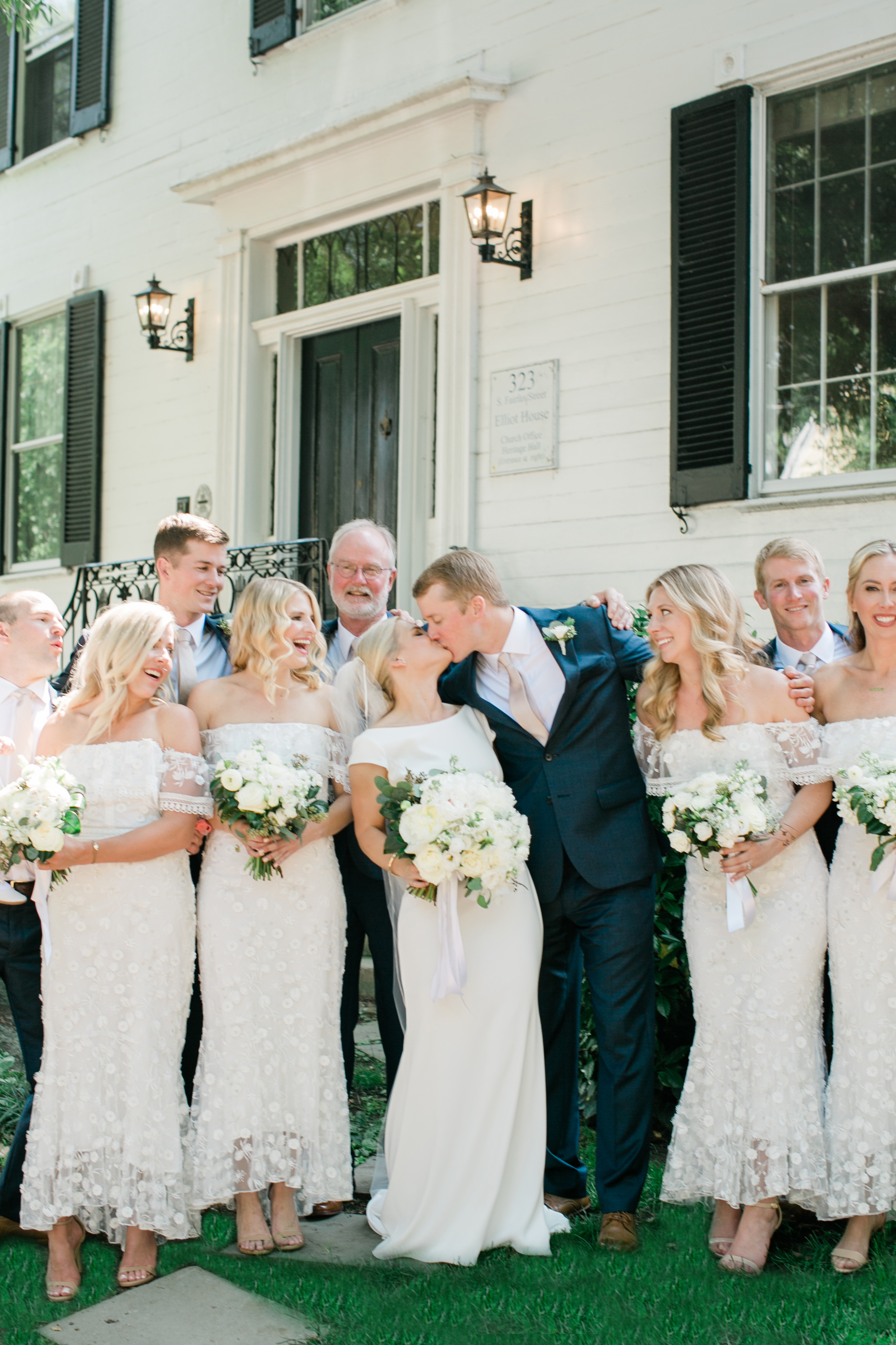 Bride and groom kiss in between bridal party