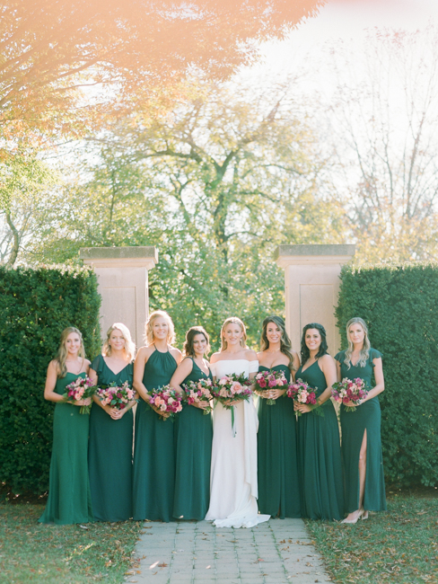 Bridesmaids with bride in front of shrubs