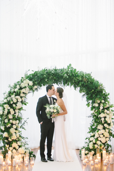 bride and groom kiss under arbour
