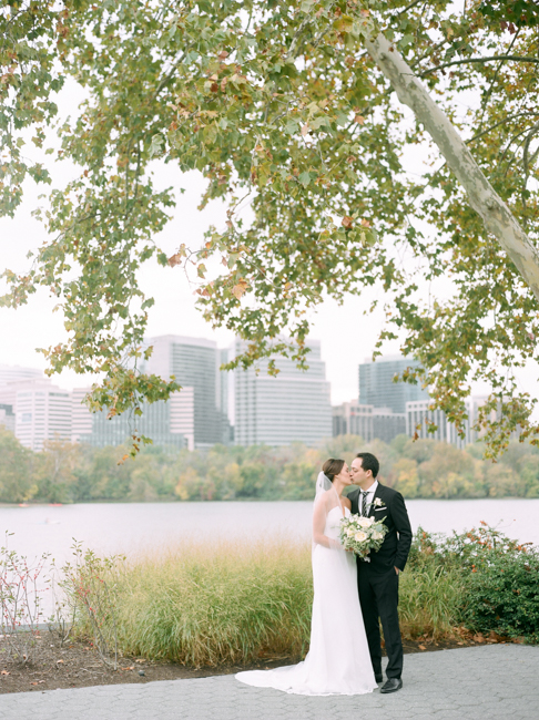 bride and groom kiss under tree
