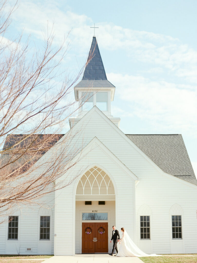 Bride and groom standing in front of church doors
