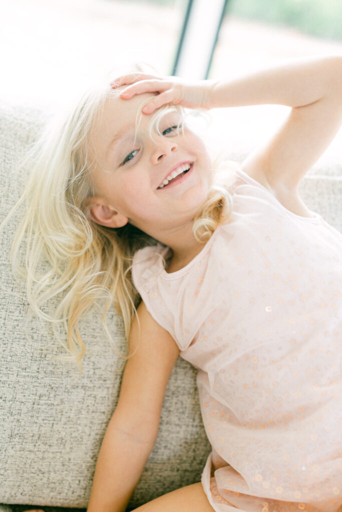 portrait of a blonde, blue eyed four year old girl laughing during a family portrait session with Astrid Woltering Photography.