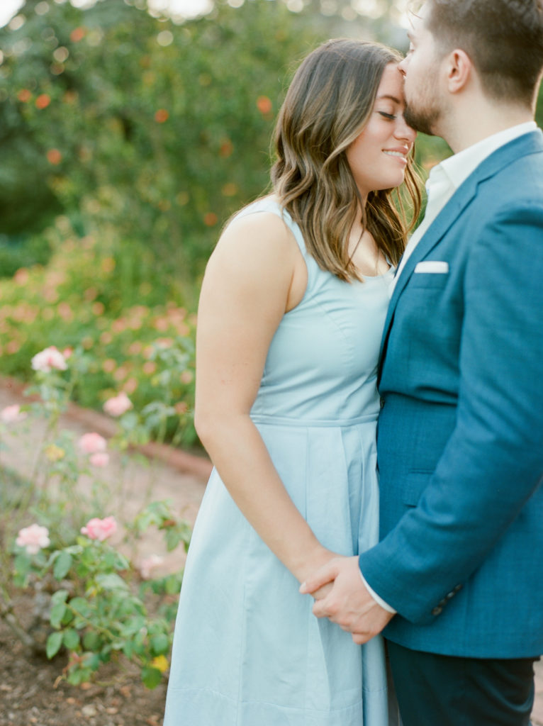 man kissing his fiance's forehead in the garden during their engagement session in washington DC